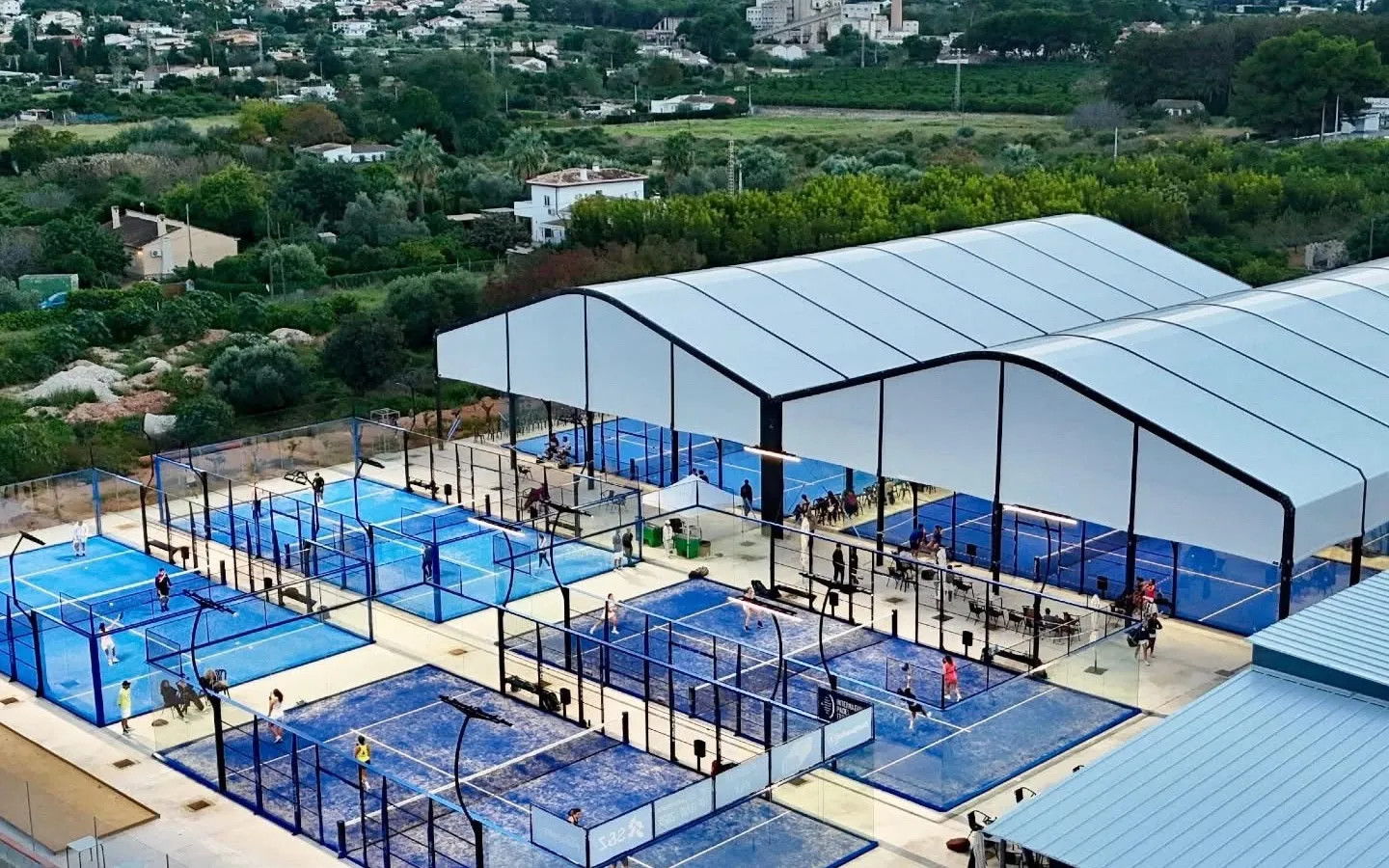 Padelanlage bei Dénia aus der Luft: mehrere Outdoor-Courts, überdachte Plätze und Spielbetrieb vor den Bergen der Costa Blanca