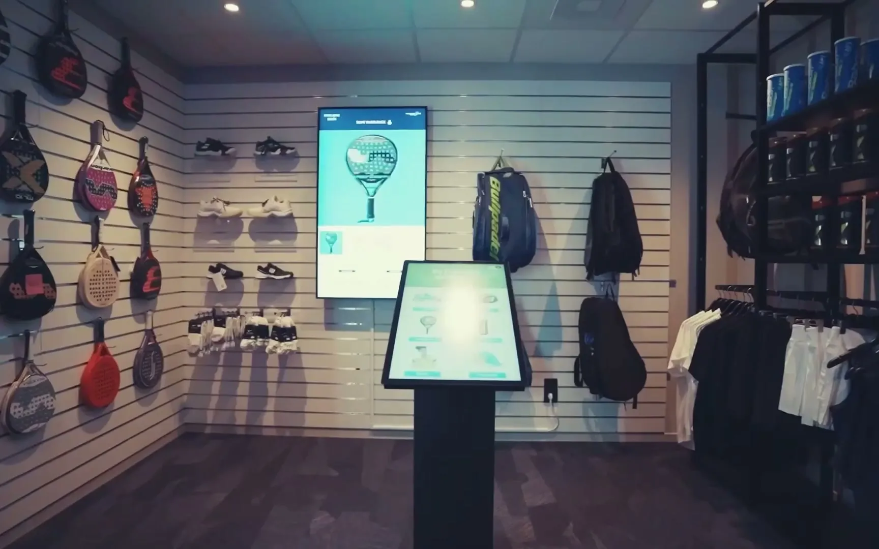 Equipment im Club-Shop: Schlägerwand, Schuhe und Griffbänder im Regal, Taschen an der Wand, Bälle und Bekleidung