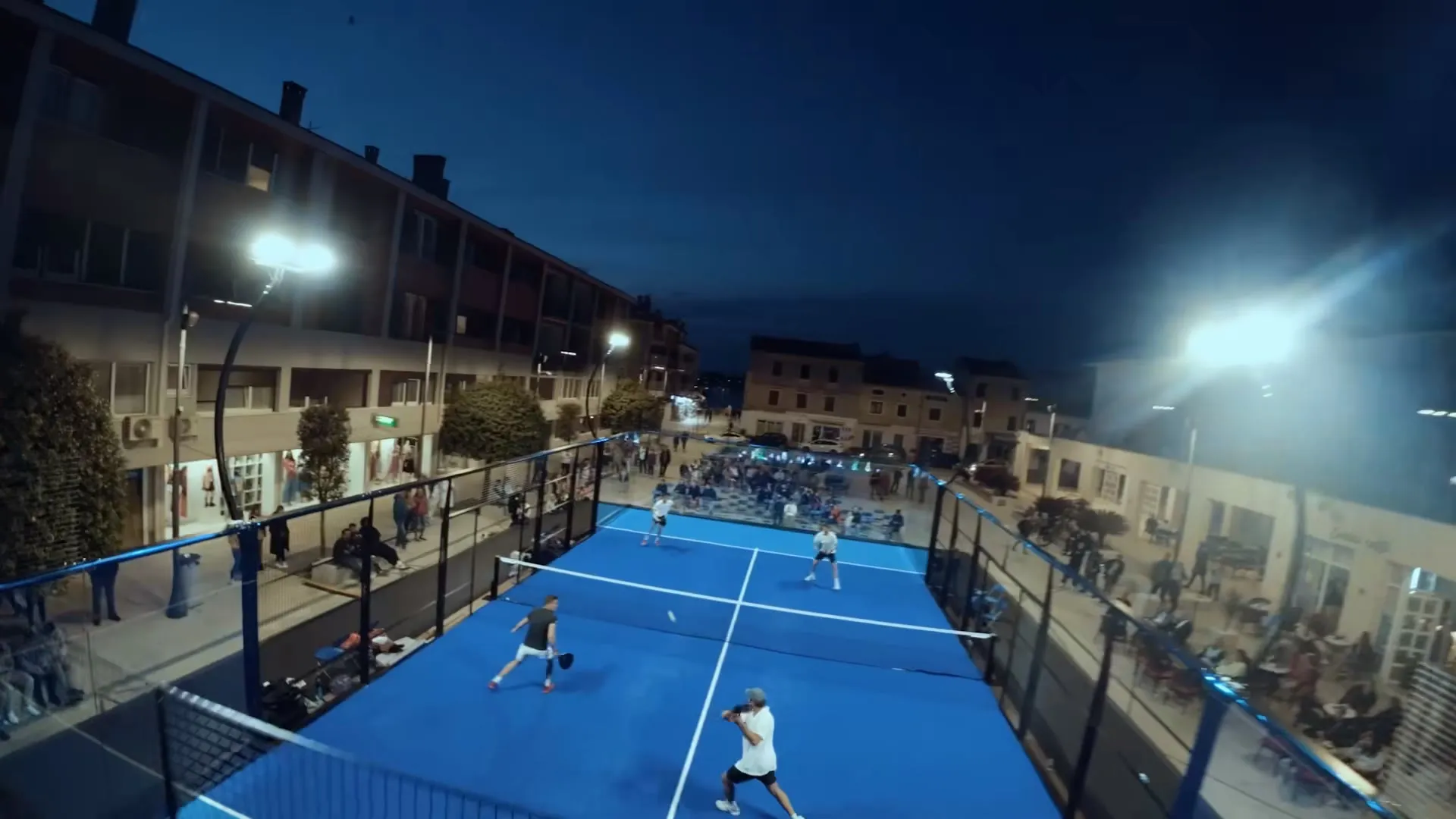 Infinity Court auf einem Stadtplatz bei Flutlicht, Doppel im Spiel, Zuschauer an den Seiten